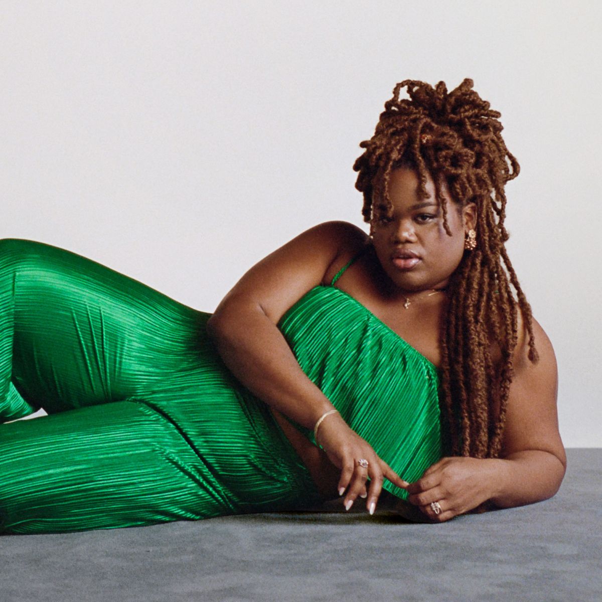 A portrait of Jari laying down on a grey carpet, facing the camera