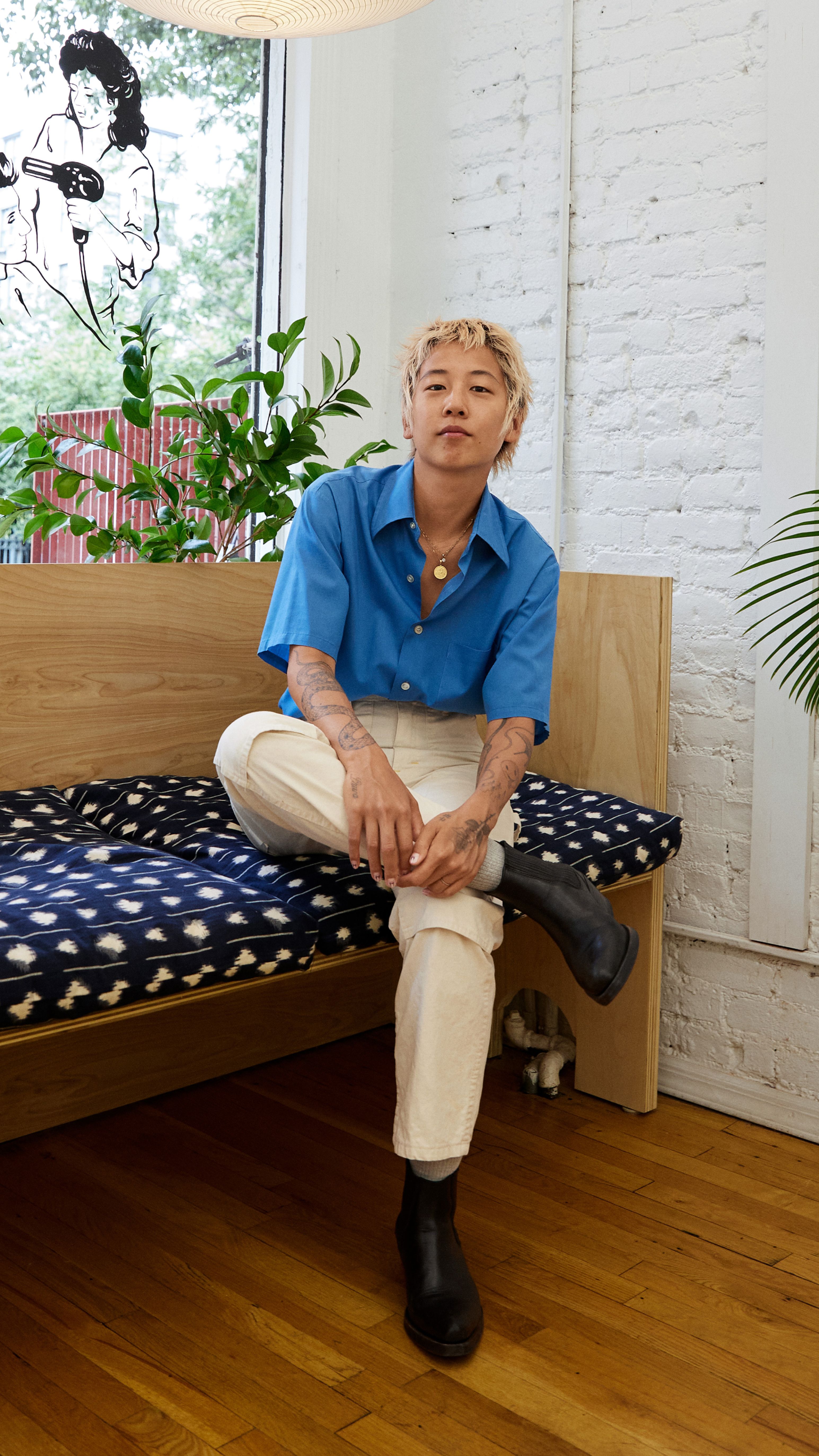 A portrait of Masami seated on a bench and looking into the camera.