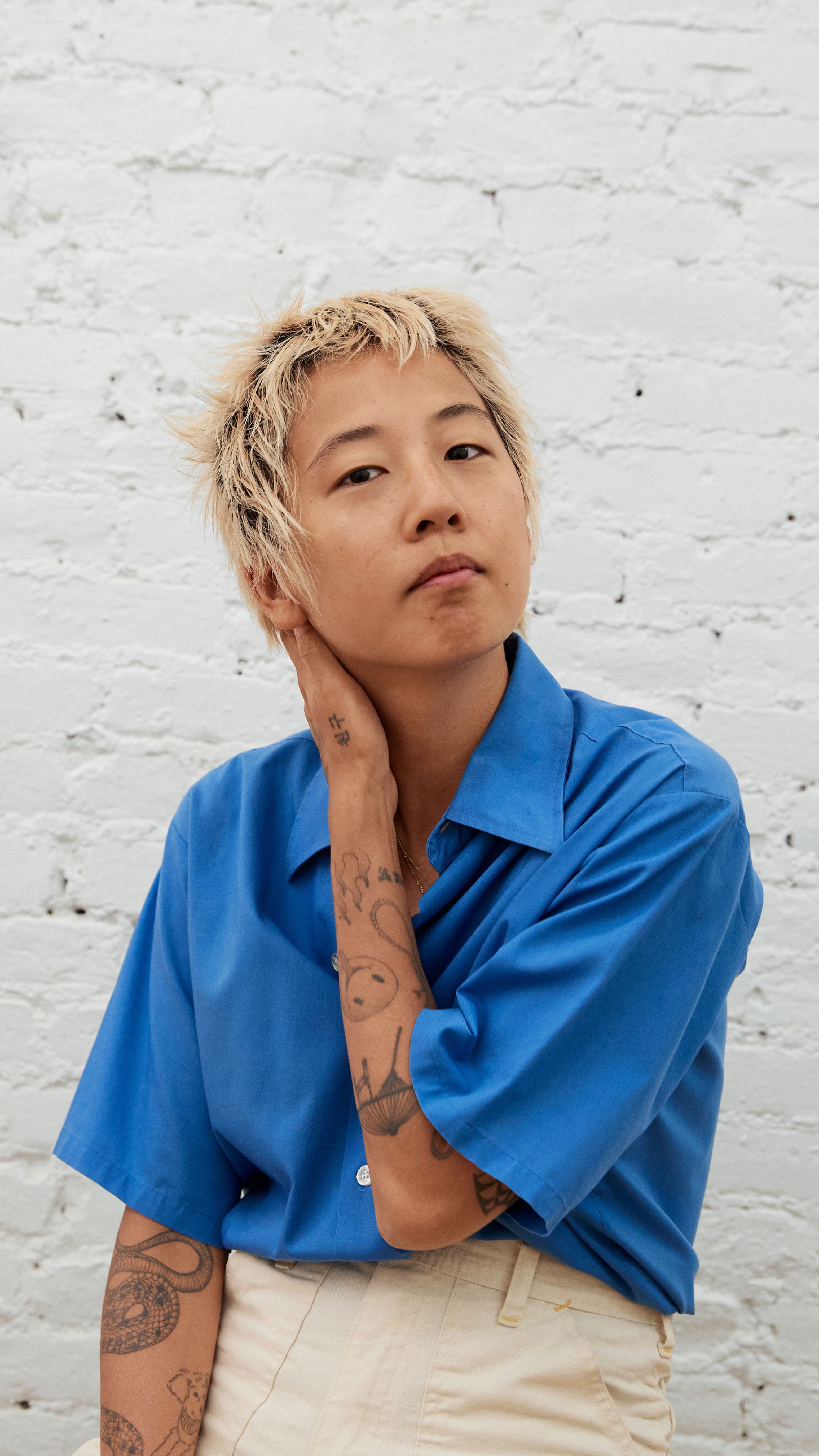 A portrait of Masami looking into the camera, They're expression and posture almost as if they're listening you talk.