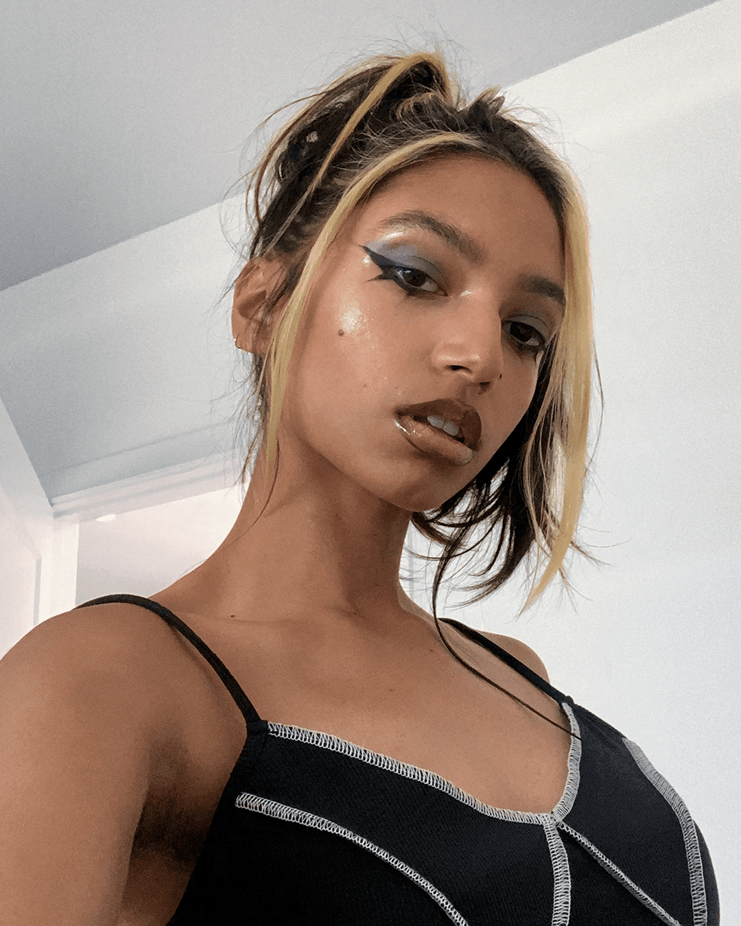 A selfie of Tara looking down into the camera. Their head is slightly tilted and their expression is confident.