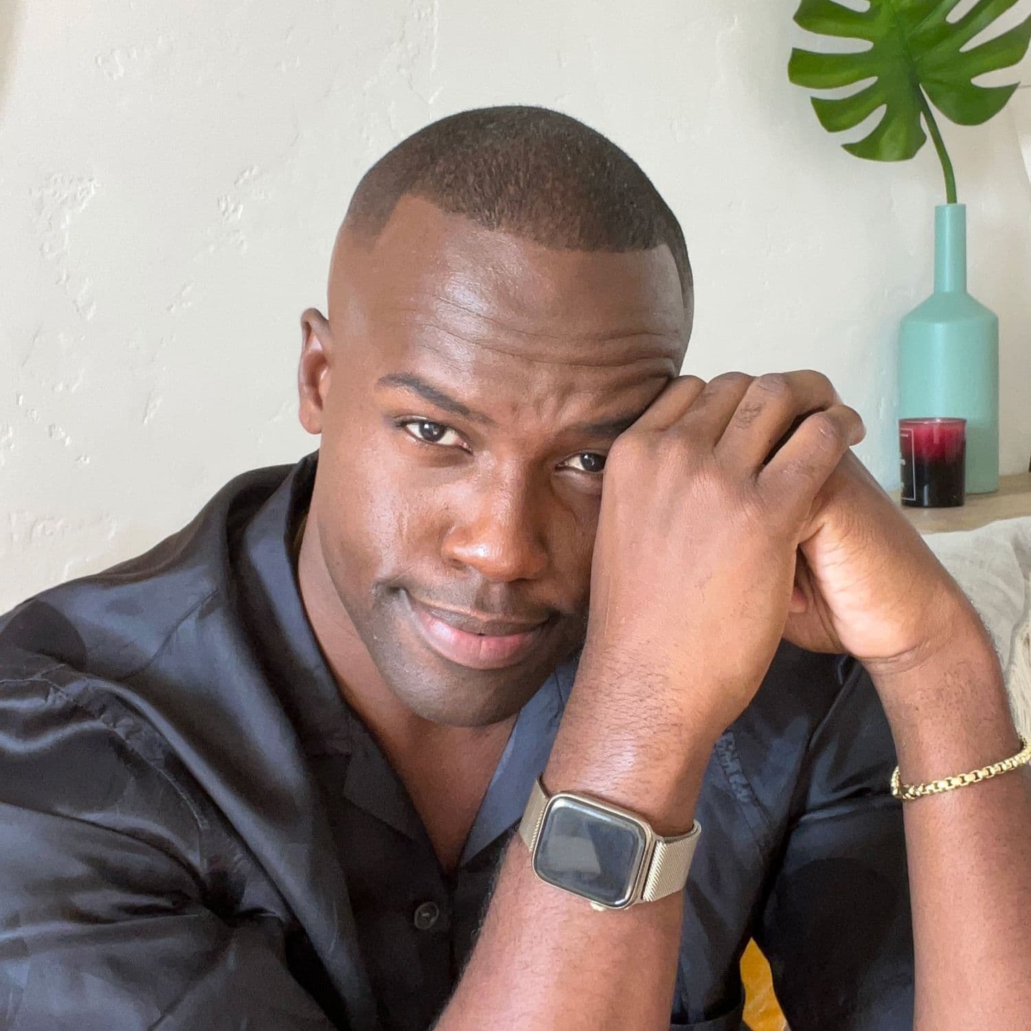 A portrait of Darien leaning up against a doorway. He's smiling with his arms crossed.