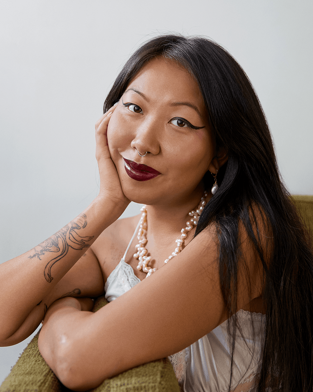 A close up portrait of Mimi. They're looking straight at the camera with a subtle, soft smile.