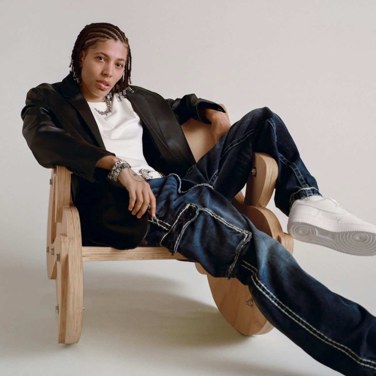 Kai sitting facing the camera, wearing a leather jacket over a white t-shirt and jeans.