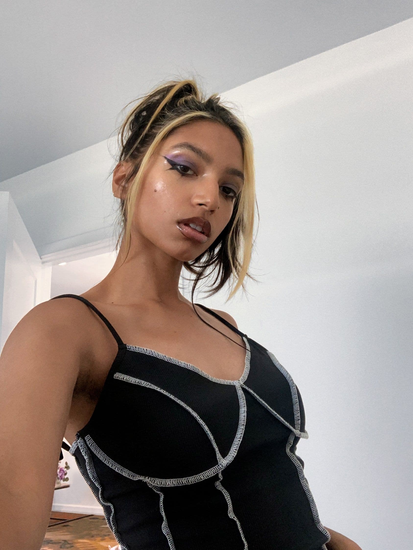 A selfie of Tara looking down into the camera. Their head is slightly tilted and their expression is confident.