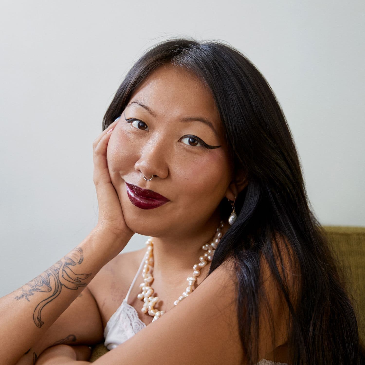 A close up portrait of Mimi. They're looking straight at the camera with a subtle, soft smile.