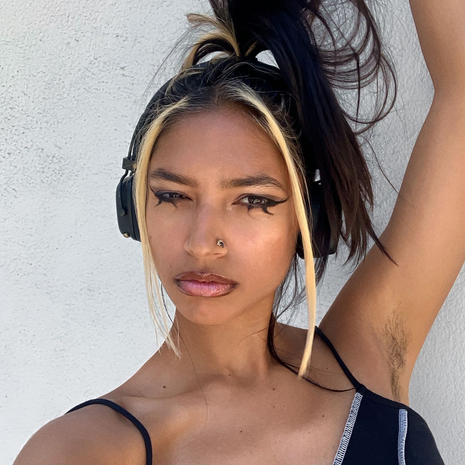 A selfie of Tara looking down into the camera. Their head is slightly tilted and their expression is confident.