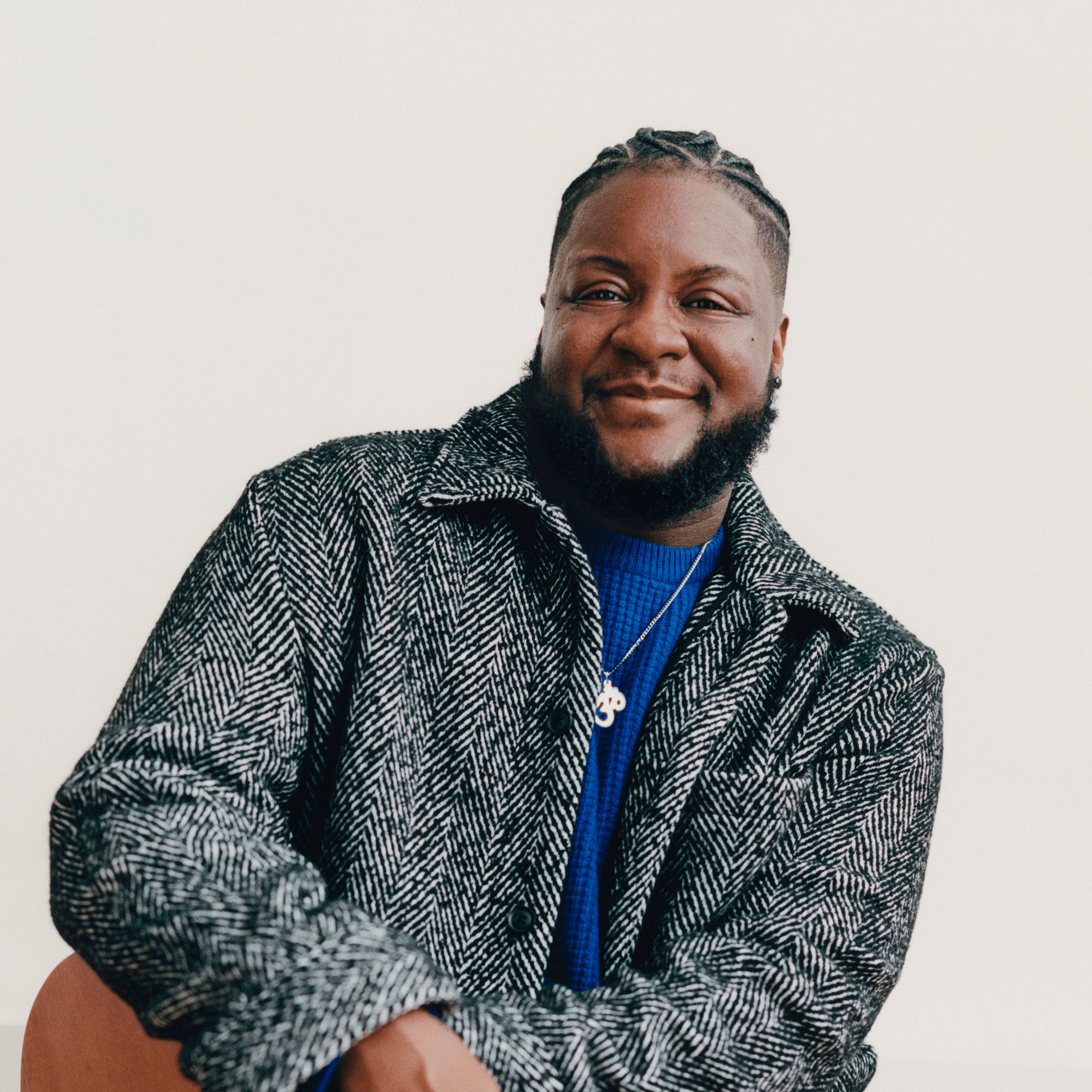 A headshot of Moe Ari Brown with a bright smile, head slightly tilted left, wearing a light denim washed button up.