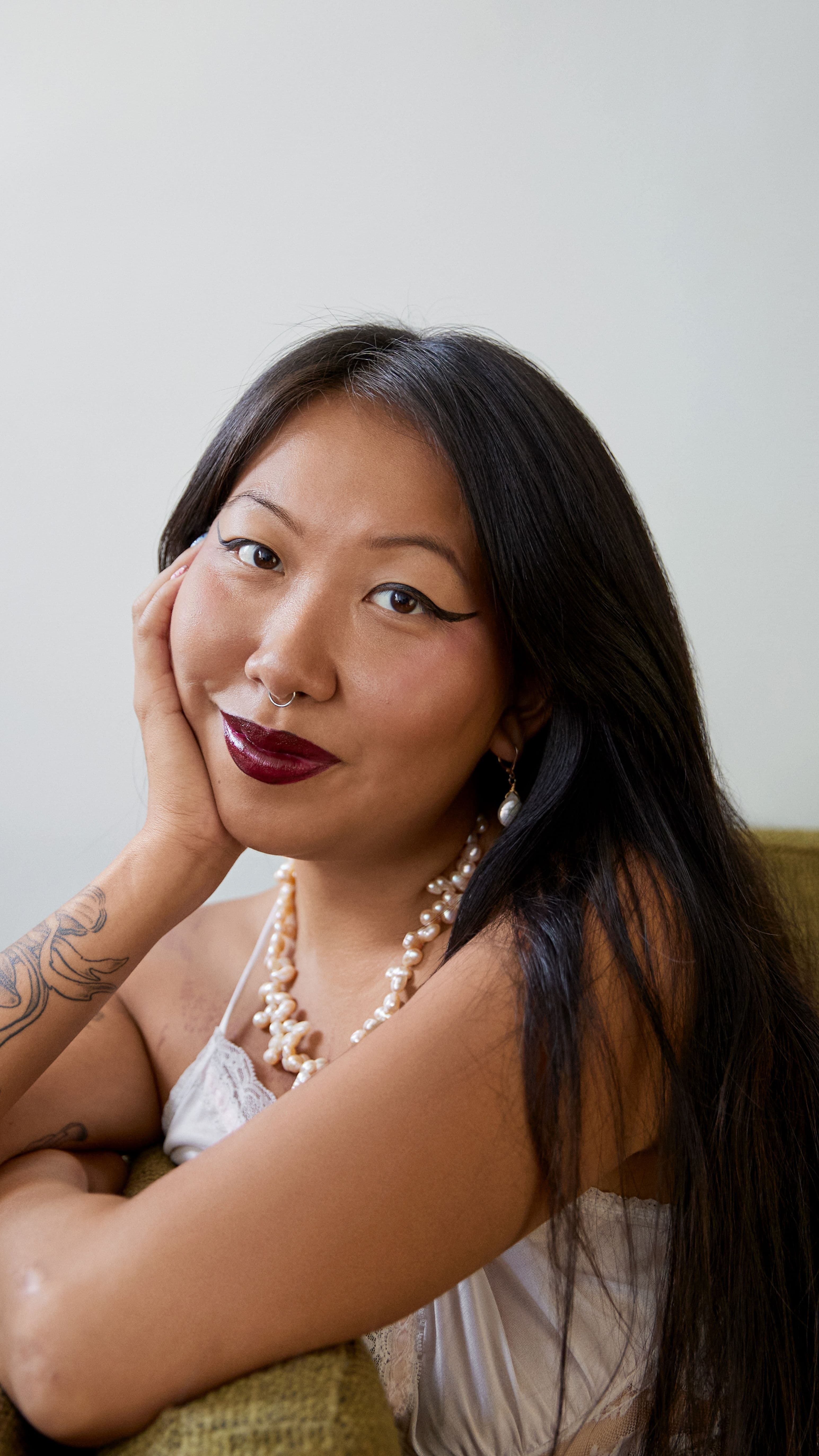 A close up portrait of Mimi. They're looking straight at the camera with a subtle, soft smile.